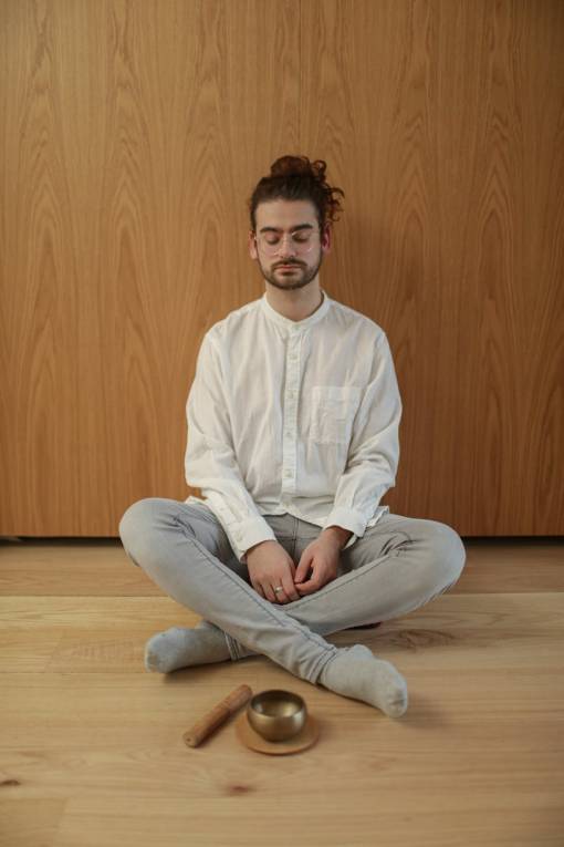 Woman meditating near a stack of coins and a small plant.